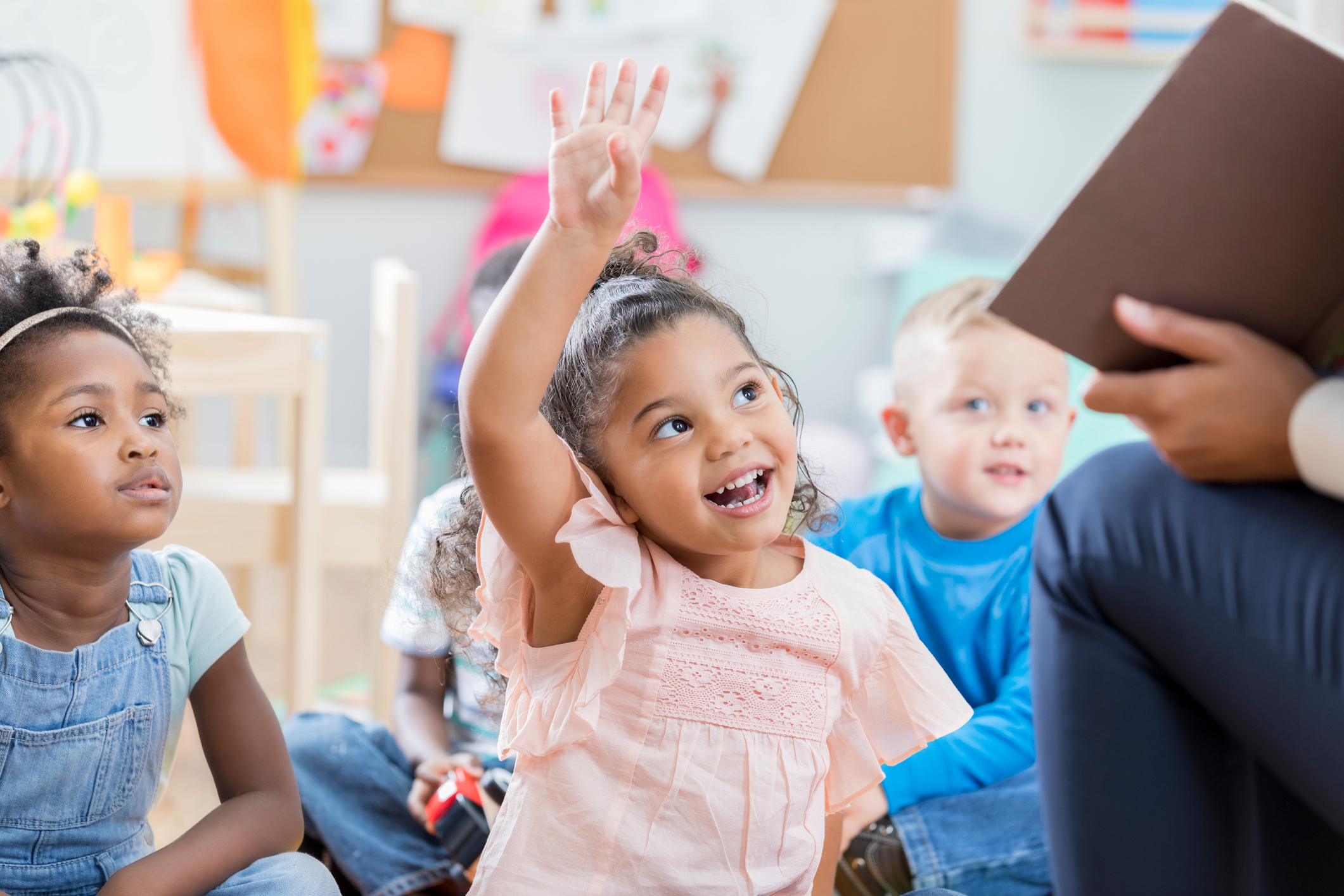 Preschool girl raising her hand in class